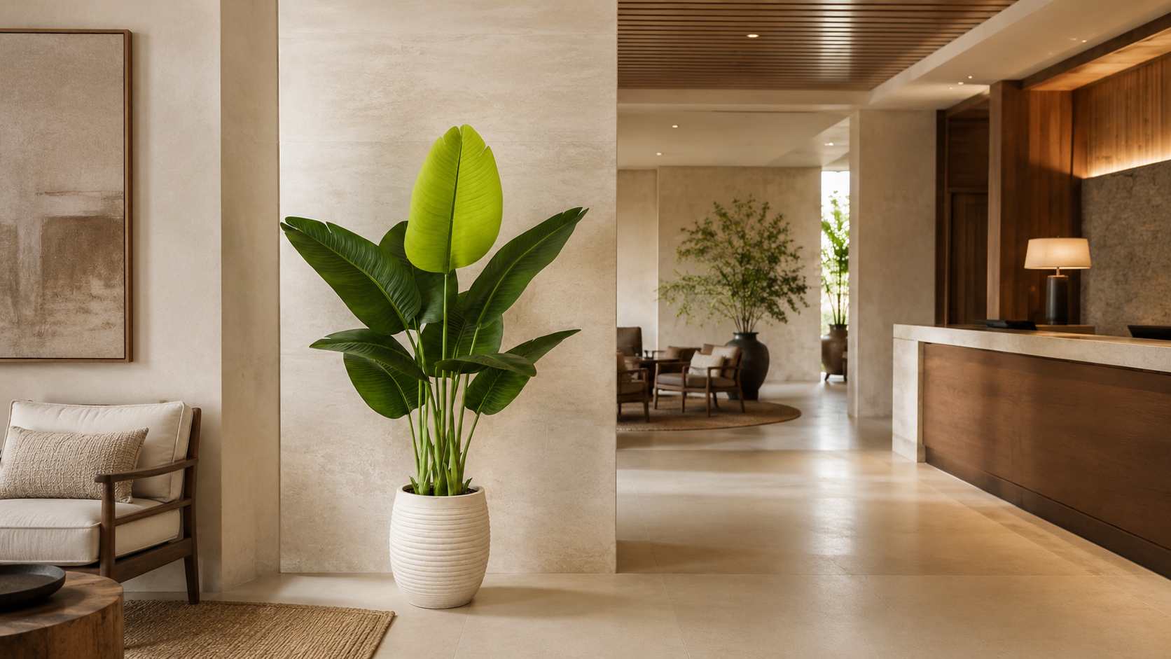 Wide view of a boutique hotel lobby with a bird of paradise plant, reception counter, and lounge seating.